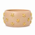 A wide, matte beige ceramic cuff bracelet decorated with raised gold star-shaped accents, shown against a plain white background.