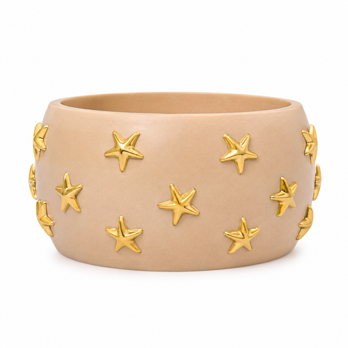 A wide, matte beige ceramic cuff bracelet decorated with raised gold star-shaped accents, shown against a plain white background.