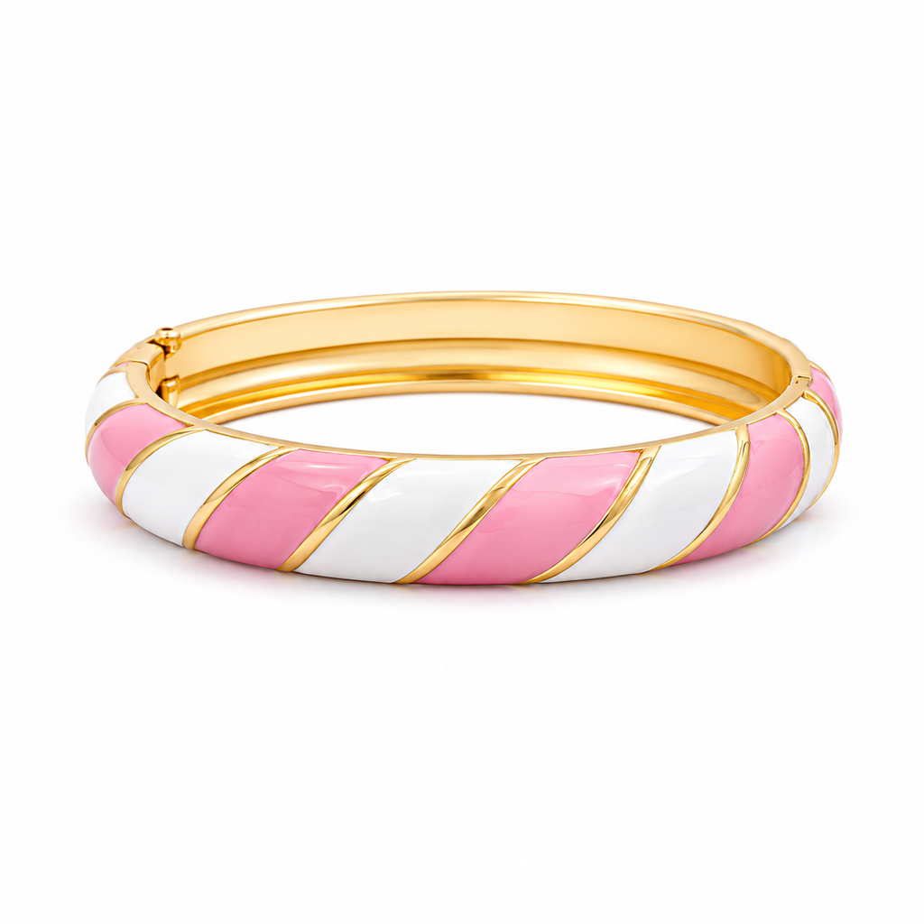 A gold-plated hinged bangle bracelet featuring diagonal stripes of white and pink enamel, set against a plain white background.