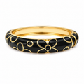A gold-plated bangle bracelet with a glossy black enamel floral pattern, shown on a clean white background.