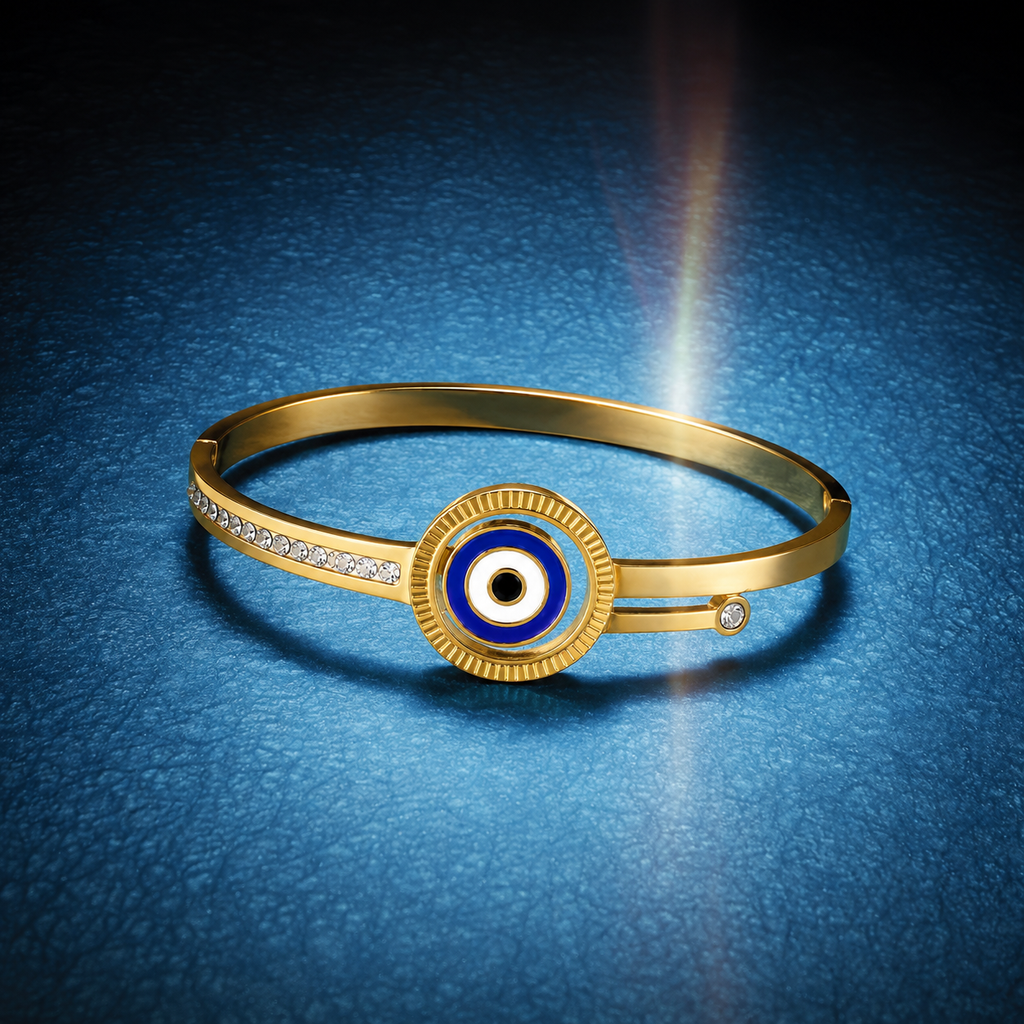 Gold hinged bangle bracelet with a central evil eye charm, set against a textured blue background with a dramatic light flare.