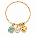 A gold-plated twisted bangle bracelet featuring three charms: a rectangular charm with a blue and gold starfish design, a white shell charm with a pearl center, and a polished gold heart charm, all displayed on a clean white background.