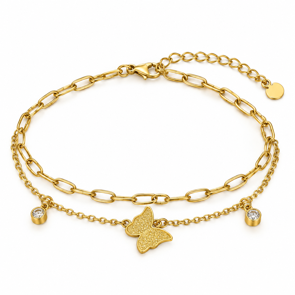A gold double-layered chain anklet featuring a textured butterfly charm, a small bezel-set clear stone charm, and an adjustable lobster clasp with a round tag, shown on a white background.