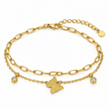 A gold double-layered chain anklet featuring a textured butterfly charm, a small bezel-set clear stone charm, and an adjustable lobster clasp with a round tag, shown on a white background.