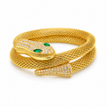 A gold snake bracelet featuring a textured mesh body, a head pavé-set with clear stones, and two green emerald-cut eyes, shown on a white background.