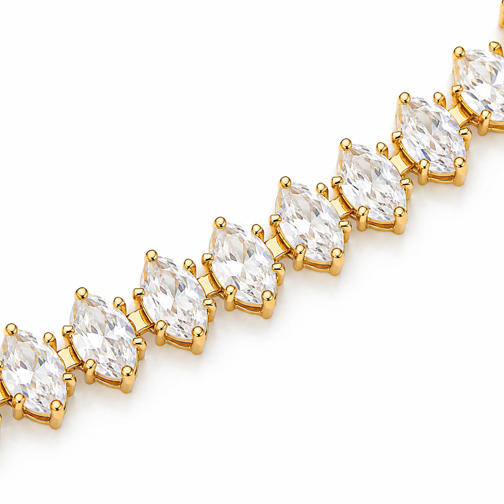 A close-up of a gold tennis bracelet featuring marquise-cut clear gemstones in prong settings, arranged diagonally on a plain white background.