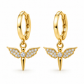 A pair of gold huggie hoop earrings with dangling angel wing charms. The charms feature gold-plated wings paved with small clear cubic zirconia stones, with a central round stone and a pointed gold tail hanging below.