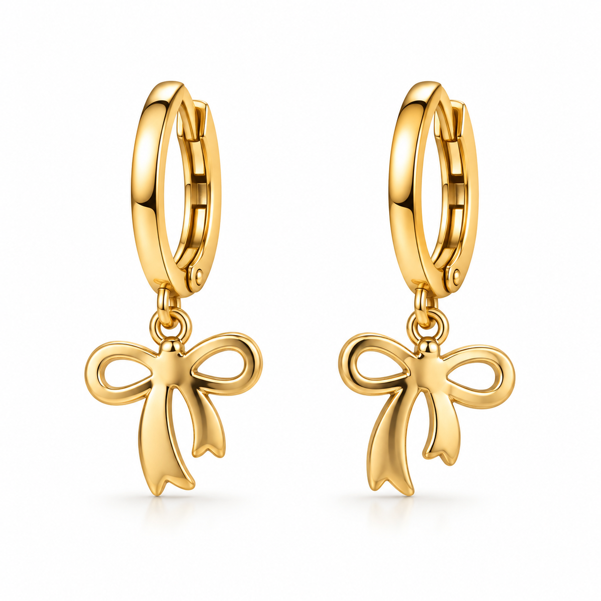 A pair of gold huggie hoop earrings with dangling bow-shaped charms, shown on a clean white background.