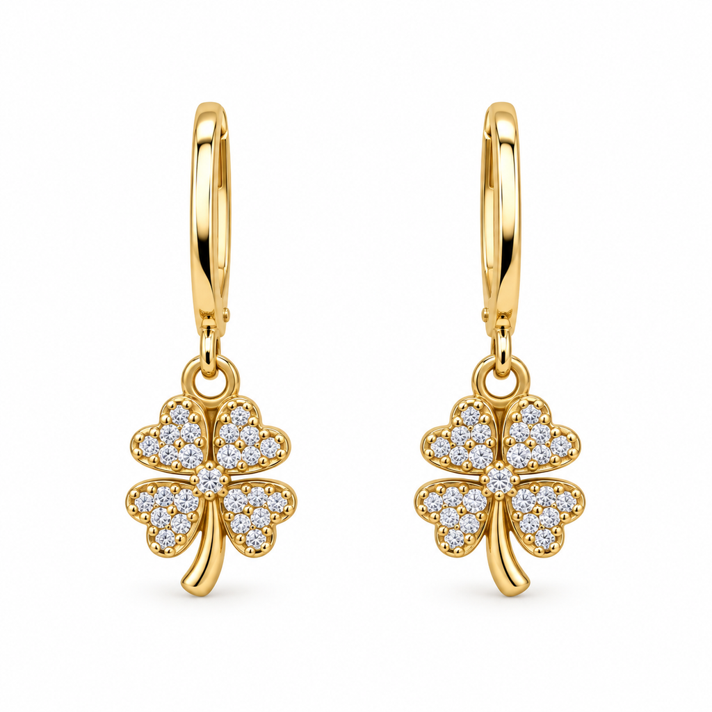 A pair of gold hoop earrings with dangling four-leaf clover charms paved with small clear stones, shown on a plain white background.
