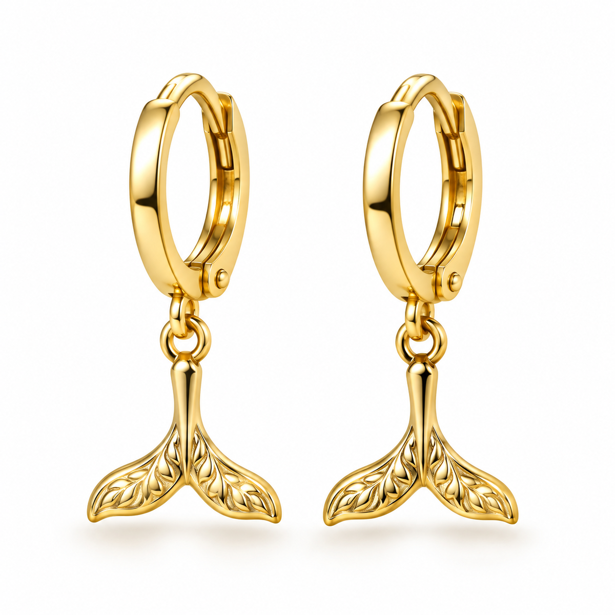 A pair of gold huggie hoop earrings with dangling mermaid tail charms, shown on a clean white background.