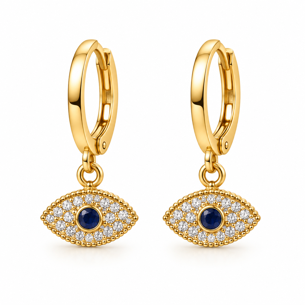 A pair of gold huggie hoop earrings with dangling evil eye charms. The charms feature a central round dark blue stone surrounded by a halo of small clear stones, all set in polished yellow gold, shown against a plain white background.