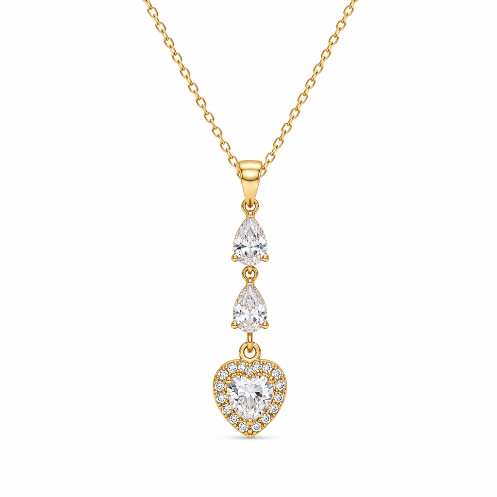 A gold dangle necklace featuring a heart-shaped pendant surrounded by small clear stones, with two pear-cut stones above on a delicate chain, set against a plain white background.