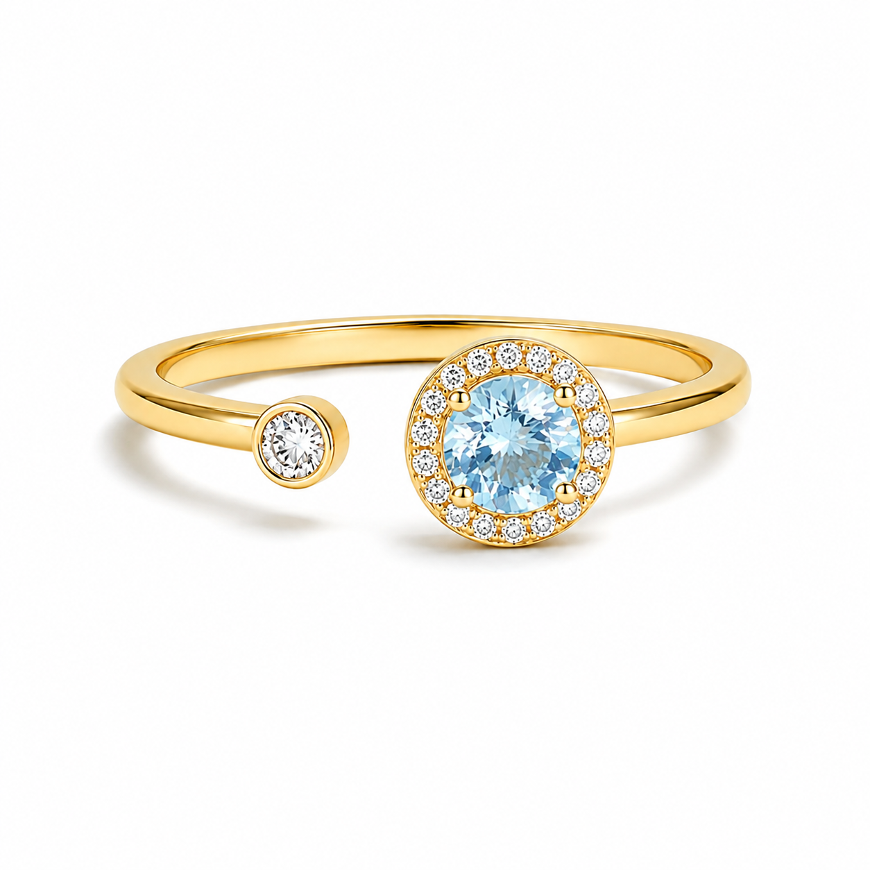 A gold open-shank ring featuring a large round light blue center stone surrounded by a halo of small clear stones, with a smaller matching round stone on the opposite side of the band, shown on a white background.