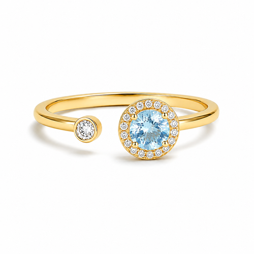A gold open-shank ring featuring a large round light blue center stone surrounded by a halo of small clear stones, with a smaller matching round stone on the opposite side of the band, shown on a white background.